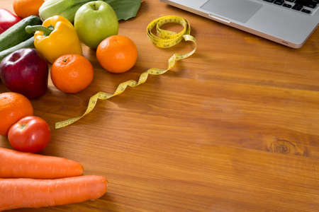 Fitness and weight loss concept, fruit and tape measure on a wooden table, top view, free copy space
