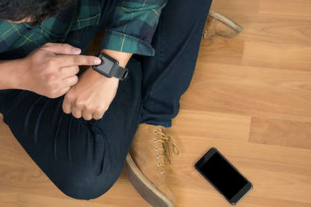 Young stylish man checking his smartwatch in cafe bar. High angle shot. Toned image.の写真素材