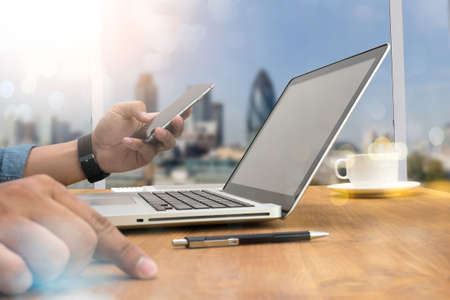 Double exposure of designer hand working and smart phone and laptop on wooden desk in office, flare,の写真素材