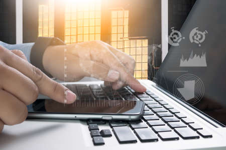 business documents on office table with smart phone and digital tablet with laptop computer and man workingの写真素材