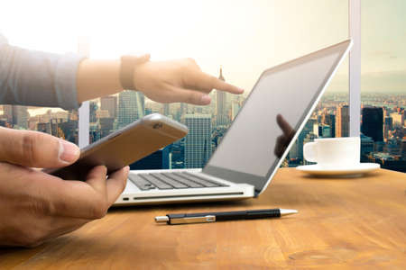 Cropped shot Silhouette of a man's hands using a laptop at home, rear view of business man hands busy using laptop at office desk, typing on computer sitting wooden table, phone on table, filter sunの写真素材