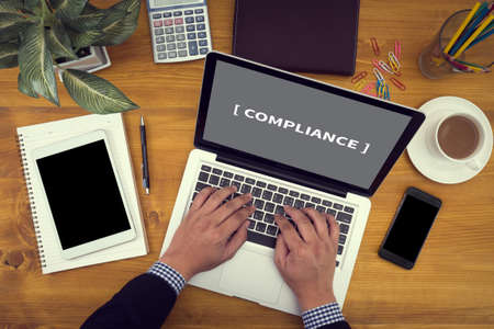 Compliance Concept Close up of business man hand working on  laptop computer on wooden desk as conceptの写真素材