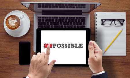 Impossible concept on the tablet pc screen held by businessman hands - online, top viewの写真素材