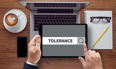 TOLERANCE CONCEPT  on the tablet pc screen held by businessman hands - online, top viewの写真素材