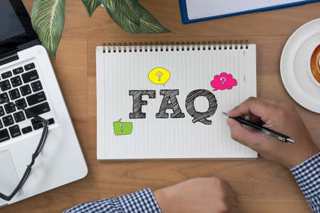 FAQ CONCEPT  hand notebook and other office equipment such as computer keyboard, digital tablet, pencil, mug of coffee on office desk.の写真素材