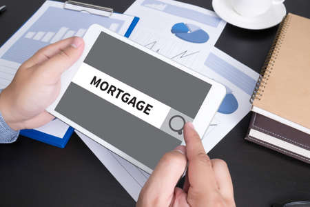 Modern people doing business, graphs and charts being demonstrated on the screen of a touch-pad, MORTGAGE CONCEPTの写真素材