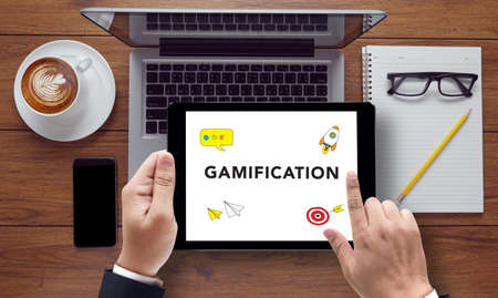 Gamification Concept,  on the tablet pc screen held by businessman hands - online, top viewの写真素材