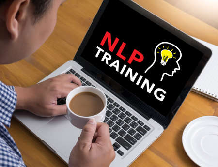 NLP TRAINING CONCEPT Businessman at work. Close-up top view of man working on laptop while sitting at the wooden desk , coffeeの写真素材
