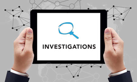 INVESTIGATIONS CONCEPT        on the tablet pc screen by businessman hands, top viewの写真素材