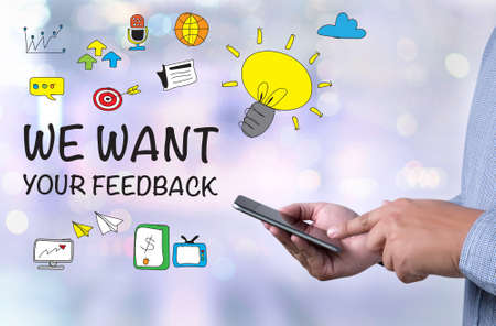 WE WANT YOUR FEEDBACK Concept person holding a smartphone on blurred cityscape backgroundの写真素材