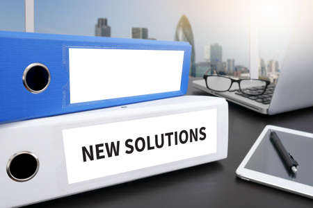 NEW SOLUTIONS Office folder on Desktop on table with Office Supplies.の写真素材