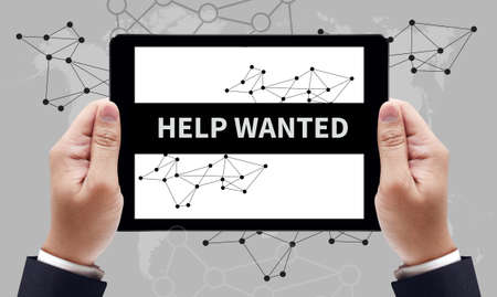 HELP WANTED CONCEPT on the tablet pc screen by businessman hands, top viewの写真素材