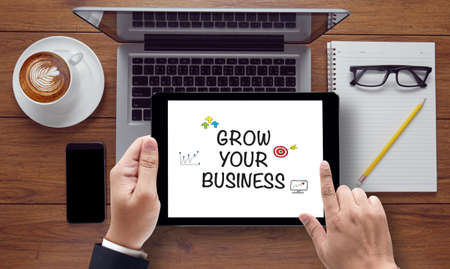 GROW YOUR BUSINESS CONCEPT , on the tablet pc screen held by businessman hands - online, top viewの写真素材