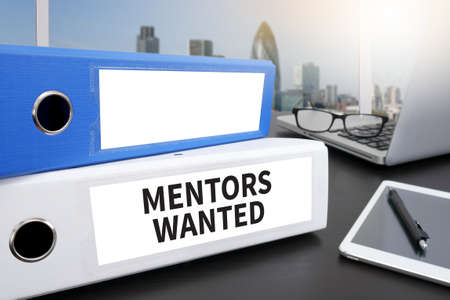MENTORS WANTED Office folder on Desktop on table with Office Supplies.の写真素材