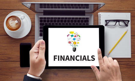 FINANCIALS , on the tablet pc screen held by businessman hands - online, top viewの写真素材