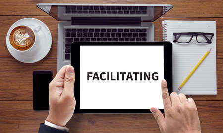 FACILITATING , on the tablet pc screen held by businessman hands - online, top viewの写真素材