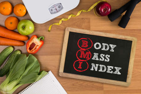 top view, fitness and weight loss concept, dumbbells, white scale, towels, fruit, BMI body mass index formula rate formula in a boardの写真素材