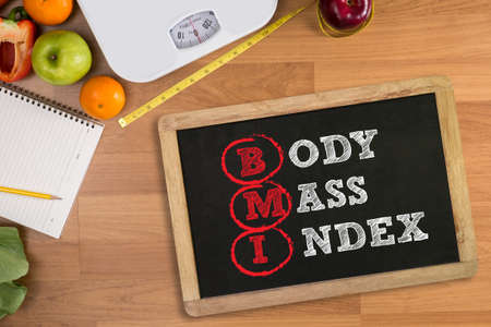 top view, fitness and weight loss concept, dumbbells, white scale, towels, fruit, BMI body mass index formula rate formula in a boardの写真素材