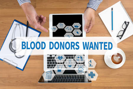 BLOOD DONORS WANTED Doctor touch digital tablet, desktop with medical equipment on background, top view, coffeeの写真素材