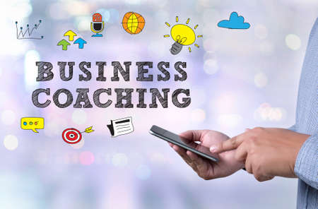 BUSINESS COACHING person holding a smartphone on blurred cityscape backgroundの写真素材