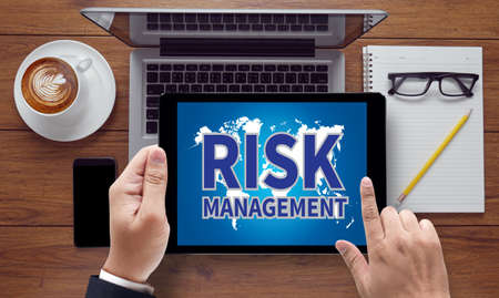 RISK MANAGEMENT, on the tablet pc screen held by businessman hands - online, top viewの写真素材