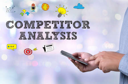 COMPETITOR ANALYSIS person holding a smartphone on blurred cityscape backgroundの写真素材