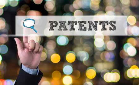 PATENTS Business man with hand pressing a button on blurred abstract backgroundの写真素材