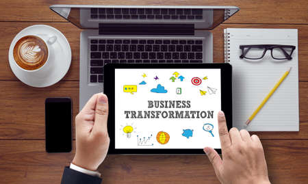 BUSINESS TRANSFORMATION vintage blackboard with wooden frame on white background., on the tablet pc screen held by businessman hands - online, top viewの写真素材