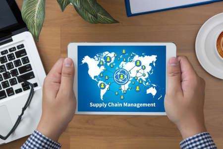 SCM Supply Chain Management concept man hand Tablet with blank black screen and coffee cupの写真素材