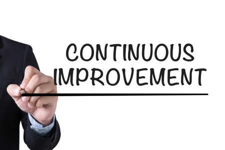 CONTINUOUS IMPROVEMENT Businessman hand writing with black marker on white backgroundの写真素材