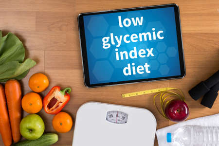 low glycemic index diet Fitness and weight loss concept, dumbbells, white scale, fruit and tape measure on a wooden table, top view, free copy spaceの写真素材