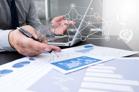 hands at work with financial reports and a laptop with other objects around, coffee, top...