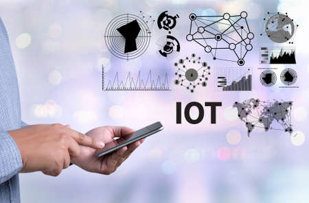 IOT hands at work with financial reports and a laptop with other objects around, coffee, top view,business man hand working and internet of things (IoT) word diagramの写真素材