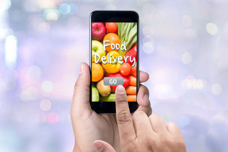 Food Delivery Food person holding a smartphone on blurred cityscape backgroundの写真素材