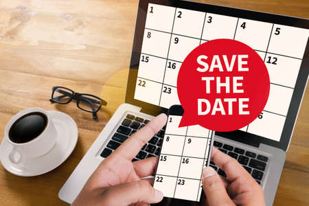 SAVE THE DATE message on hand holding to touch a phone, top view, table computer coffee ,の写真素材