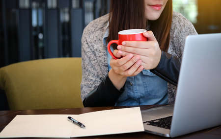 Inspired cup of fresh coffee.  young woman holding coffee cup and smile while sitting at her working sunlight lightの写真素材
