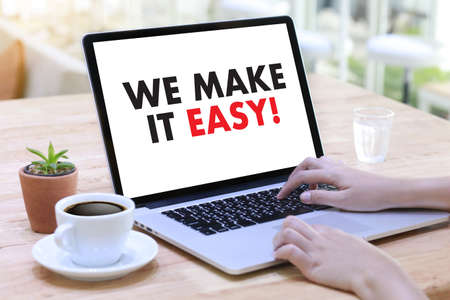 WE MAKE IT EASY! Business team hands at work with financial reports and a laptop, top viewのeditorial素材