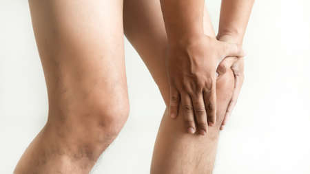 the knee man holds on suffering from pain in knee Closeup. The lesion is highlighted in red.の写真素材