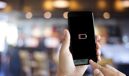 Close up man hands using smart phone battery low charged battery screenの写真素材