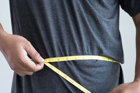 man Checking Waistline  body shape  waist measure tapeの写真素材