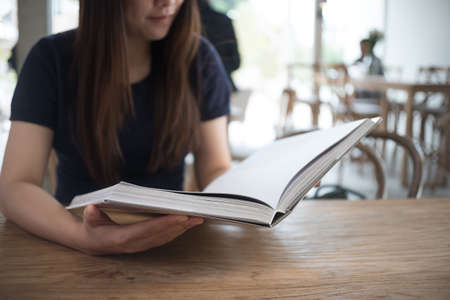 beautiful girl happy to sit reading a book Close-up of female relaxing in coffee shop cup of teaの写真素材