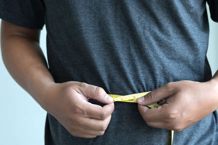 man Checking Waistline  body shape  waist measure tapeの写真素材
