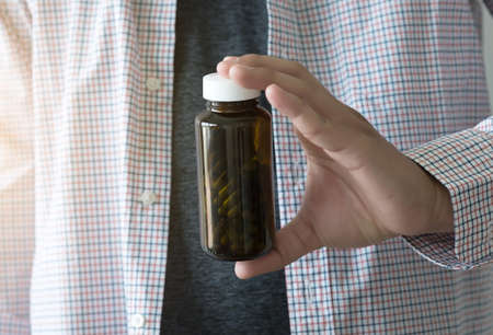 Medicine and health care concept man pours the pills out of the bottle holding medicine