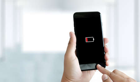 Close up man hands using smart phone battery low charged battery screenの写真素材