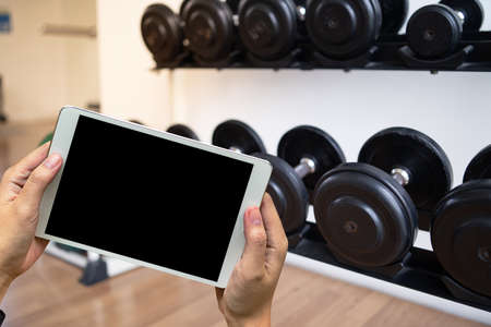 Young man Hand holding smartphone in gym to  fitness phone fitness exercise conceptの写真素材