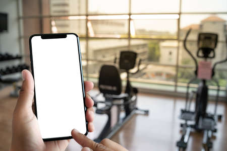 Young man Hand holding smartphone in gym to  fitness phone fitness exercise conceptの写真素材