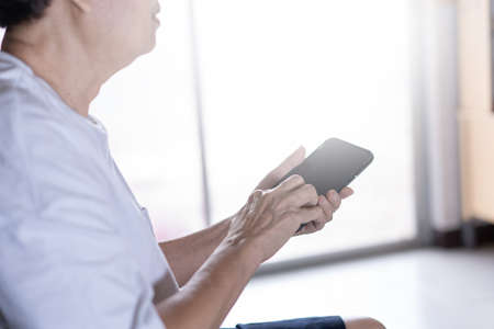 Elderly woman using her phone in home