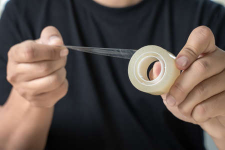 Close up of a man packaging tape roll adhesive tap
