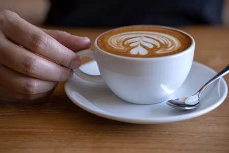 women  Holding coffee cup, wooden table  cafe while having coffeeの写真素材