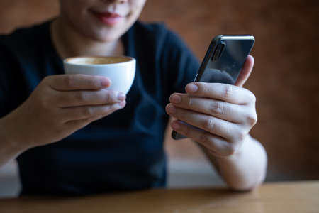 female model holds modern smart phone   relaxing in cafe coffeeの写真素材